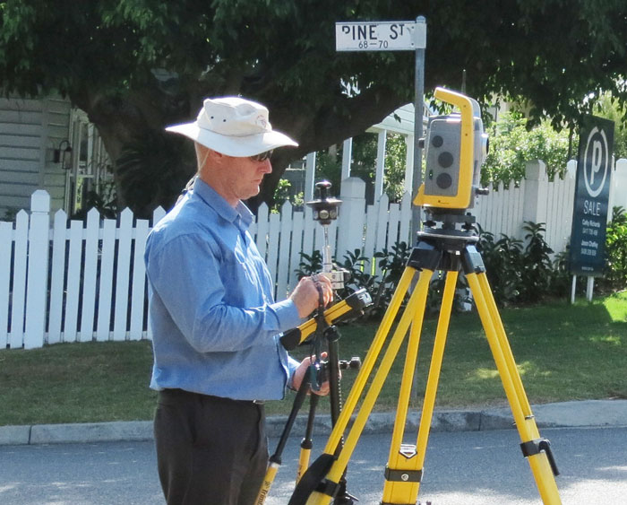 Owner Paul Reed in a quiet Brisbane suburban street using his Total Station to identify a proprty's boundaries