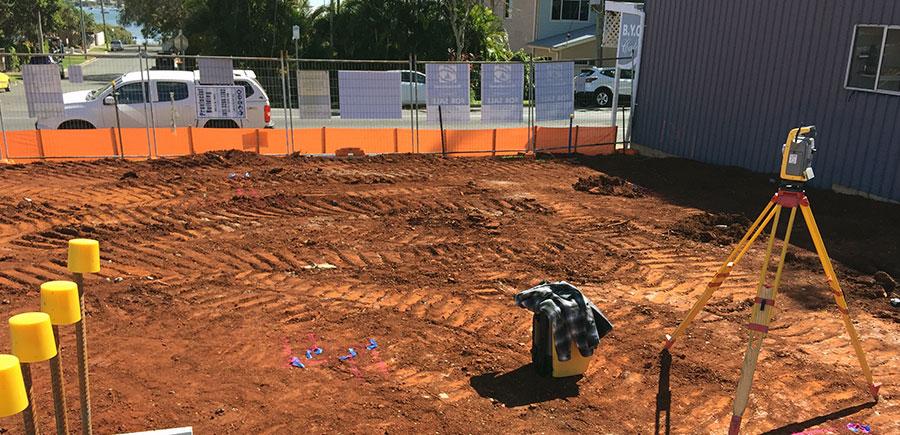 Surveyor’s total station set up on a tripod at a construction site for building setout, with marked ground points and layout lines defining foundation positions.