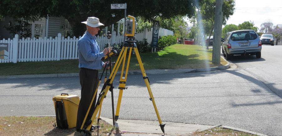 Paul Reed using a total station on a suburban Brisbane street to measure residential property boundaries for identification survey.